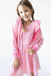 Girl wearing pink sequin jacket for girls and matching skirt smiling and posing indoors