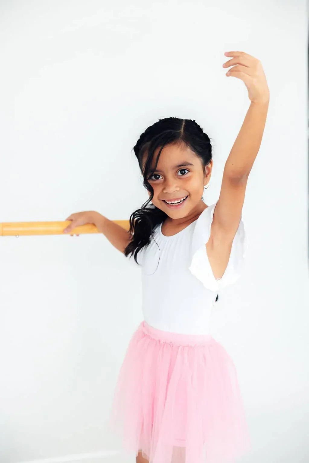 young girl wearing pink tutu shorts for girls practicing ballet pose at barre
