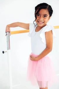 young girl wearing pink tutu shorts for girls smiling and posing at ballet barre