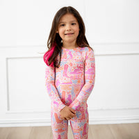 Smiling girl in pastel pink and purple Saddle Up Second-Skin long-sleeve pajama set.