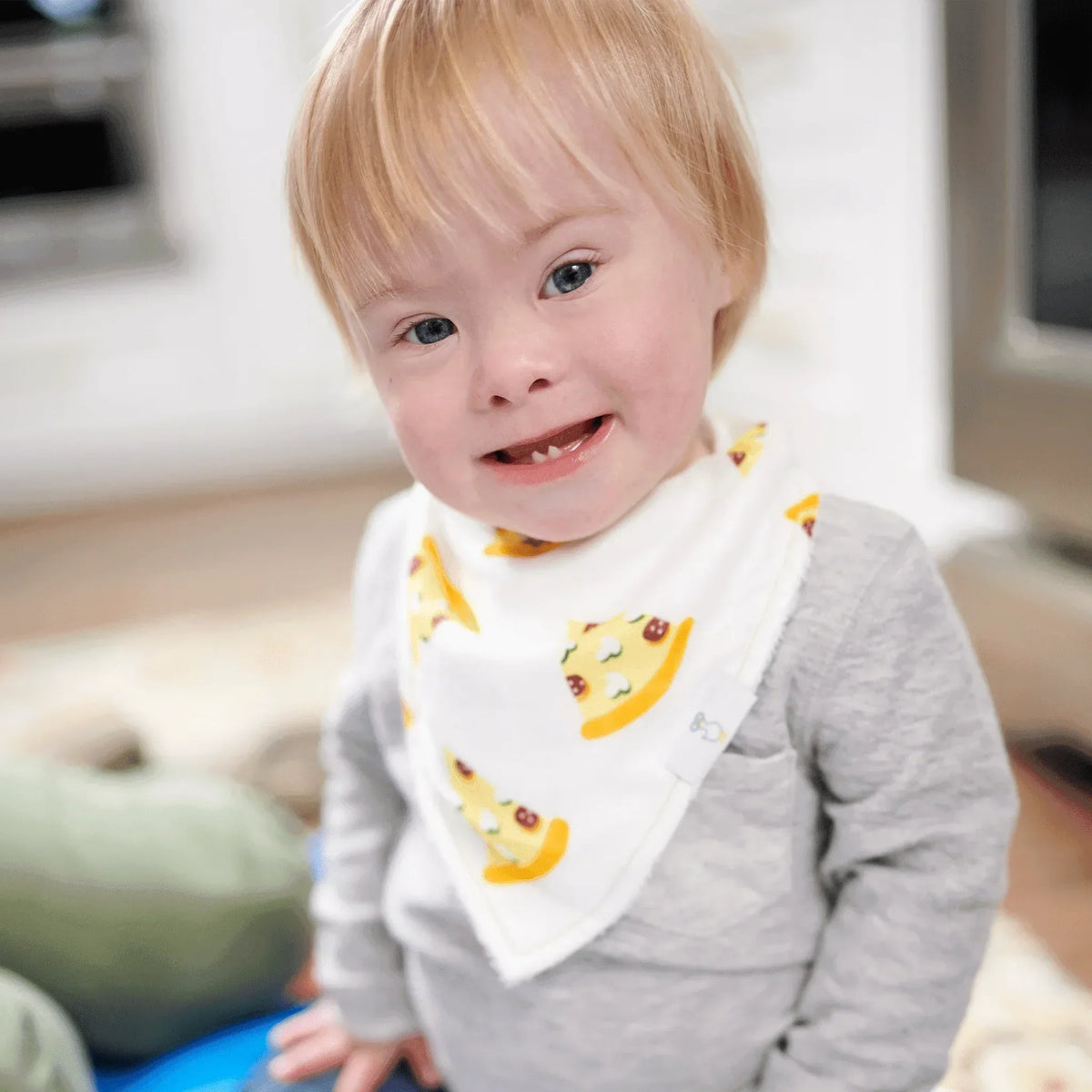 smiling toddler wearing white pizza baby bib set with colorful pizza slice prints indoors