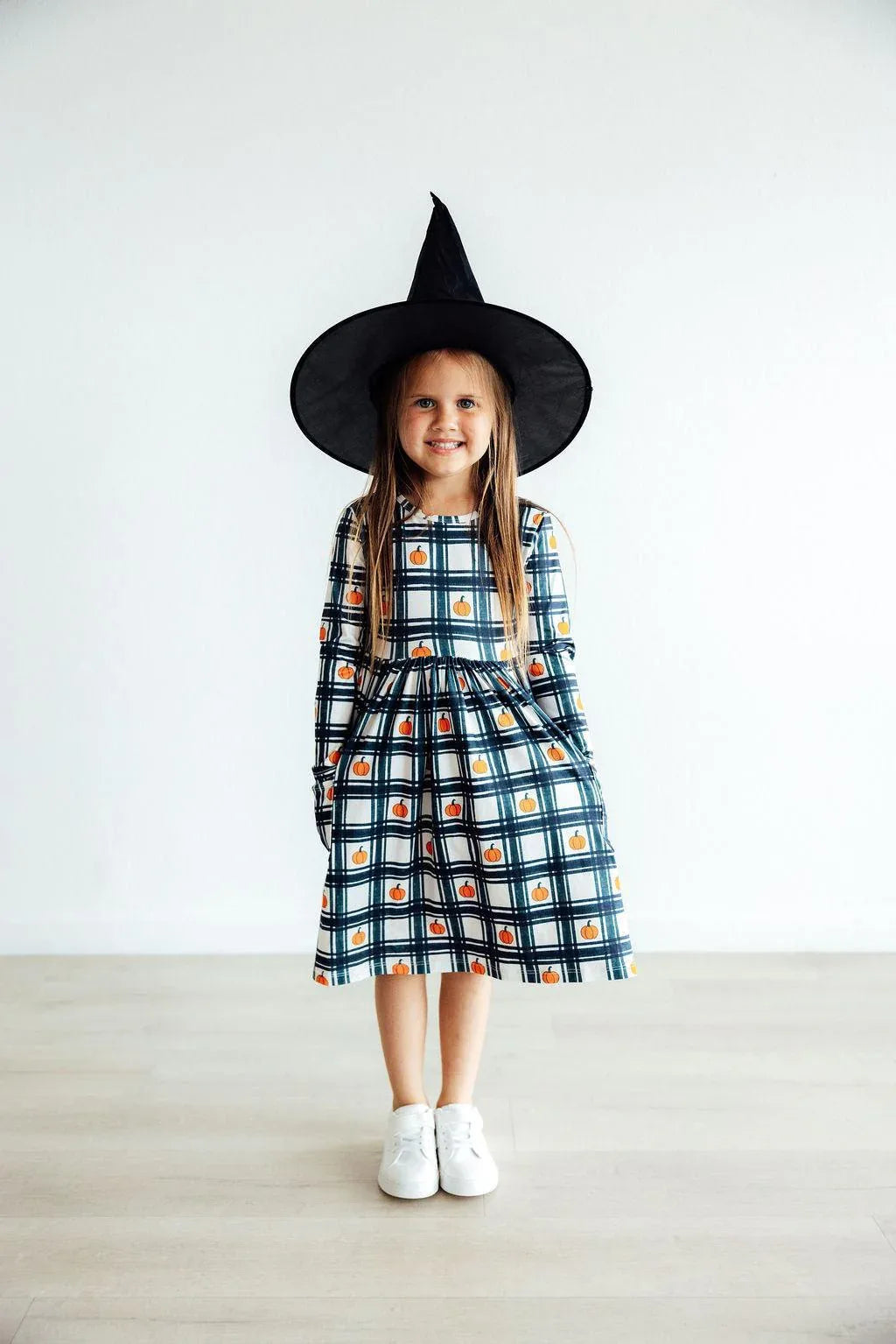 Girls plaid pumpkin dress for girls with long sleeves and pockets, worn by young child with witch hat