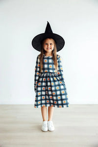 Girls plaid pumpkin dress for girls with long sleeves and pockets, worn by young child with witch hat