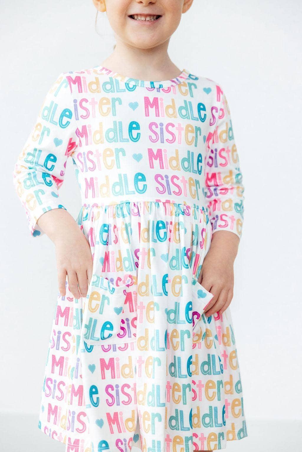 young girl wearing colorful middle sister pocket twirl dress with 3 quarter sleeves smiling