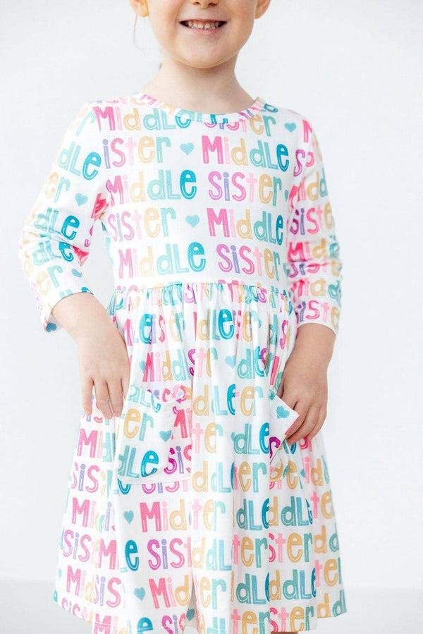 young girl wearing colorful middle sister pocket twirl dress with 3 quarter sleeves smiling