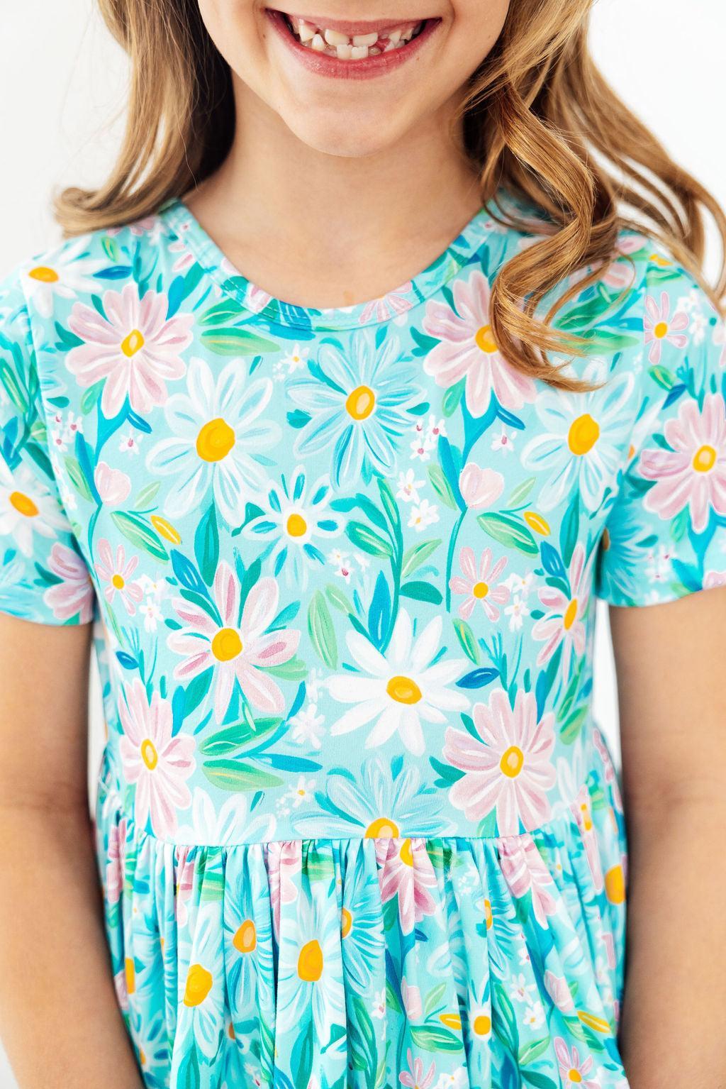 girl wearing blue preppy daisy twirl dress for girls smiling close up of top