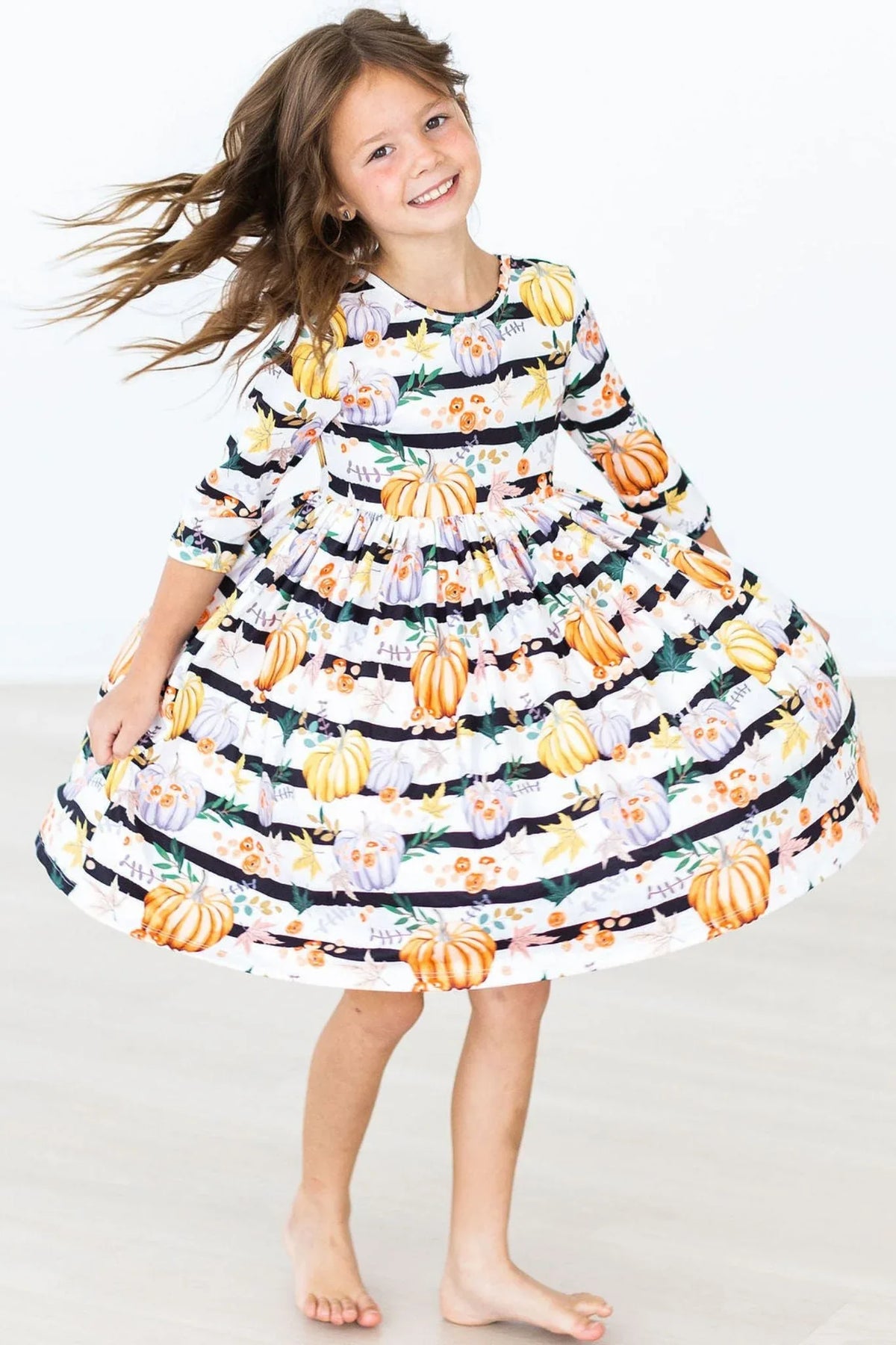 Girls pumpkin print twirl dress with 3/4 sleeves in white with black stripes and orange pumpkins