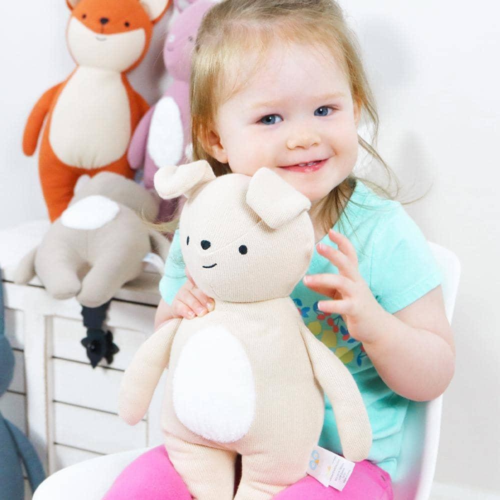 Cream and white puppy knit plush toy for babies made of soft knit material held by smiling toddler