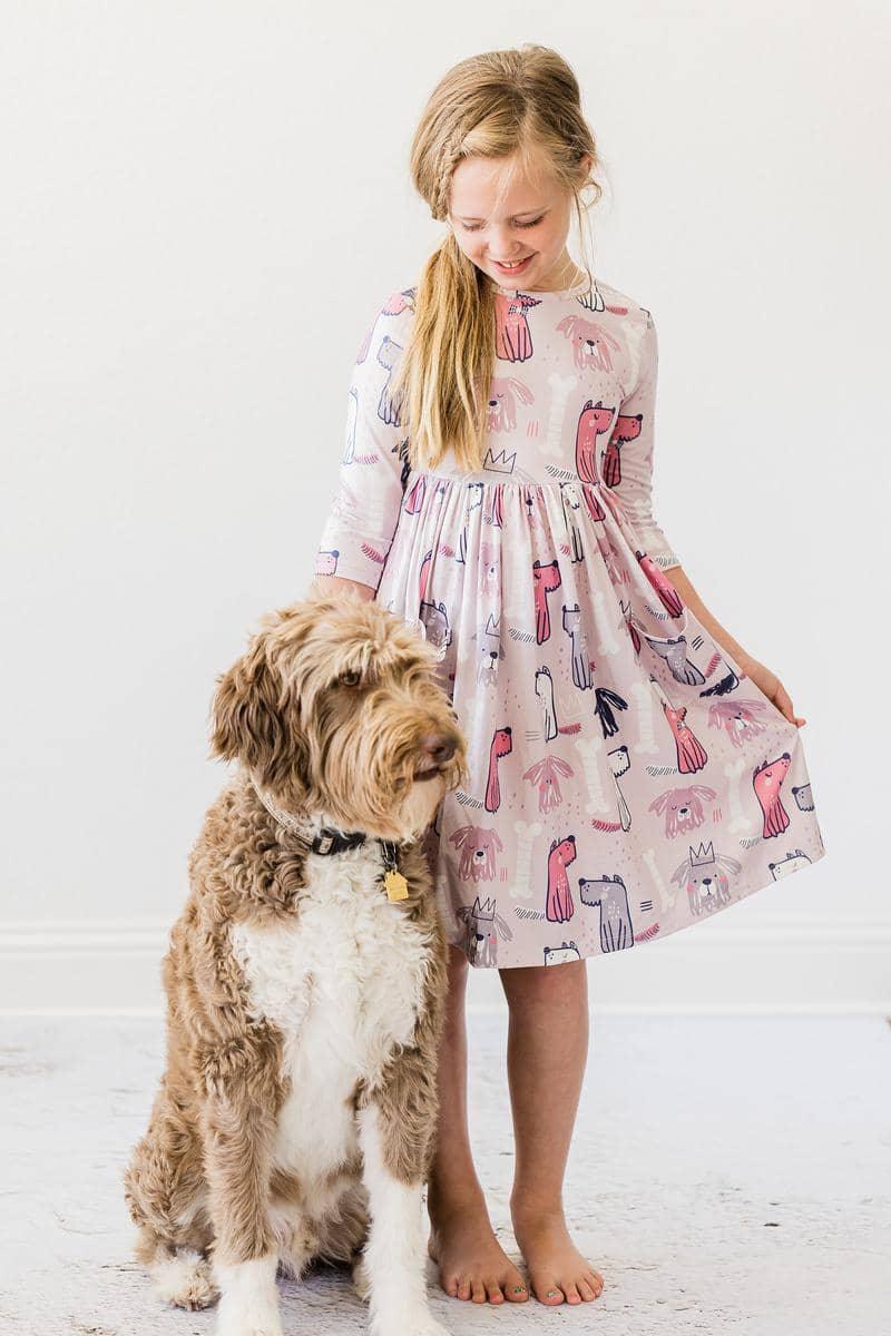 young girl wearing pink puppy party dress for girls standing next to a large brown and white dog