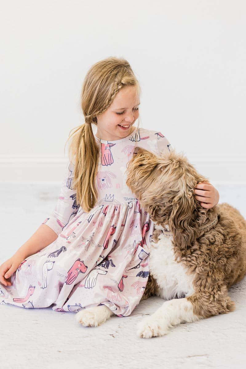 young girl wearing pink puppy party dress for girls sitting on floor hugging brown fluffy dog