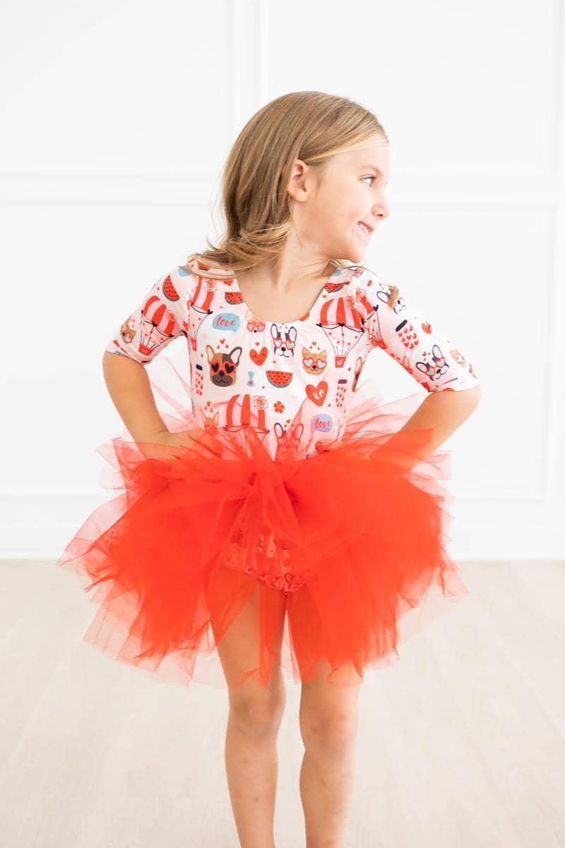 young girl wearing red puppy print tutu leotard for girls standing with hands on hips smiling