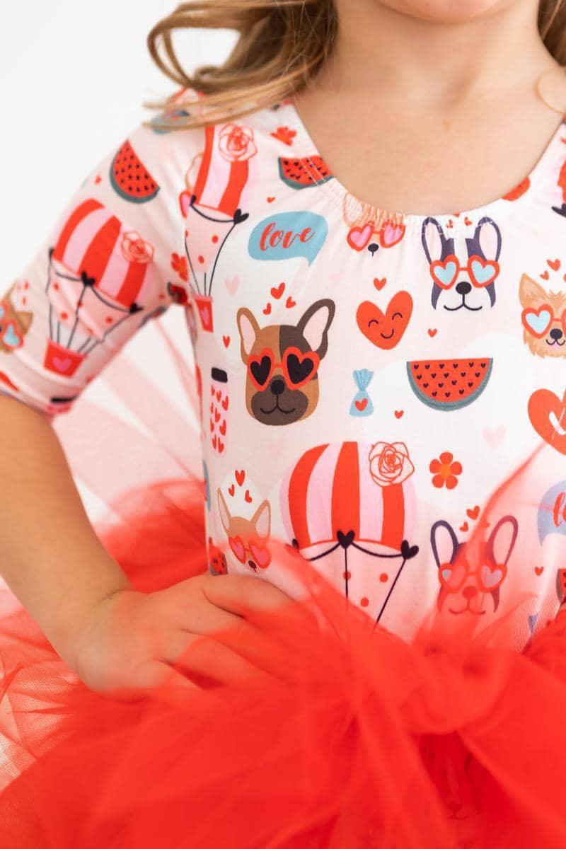 young girl wearing puppy print tutu leotard for girls in red and white with sleeves posing with hand on hip