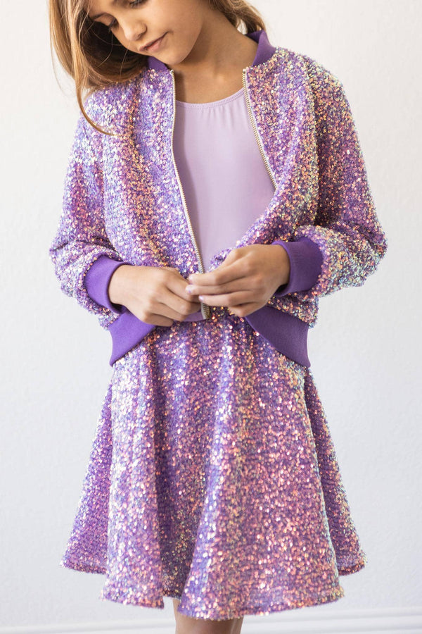 girl wearing purple sequin jacket for kids with matching skirt buttoning jacket