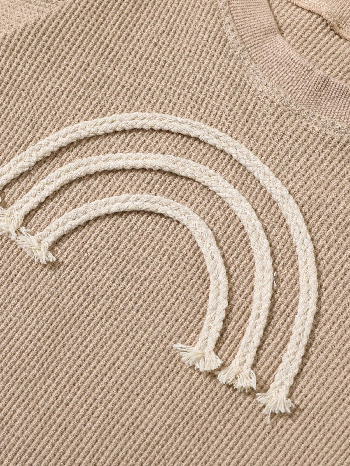 Beige baby romper with white braided rainbow design for infants rainbow baby romper