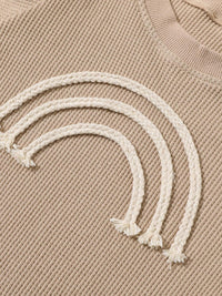 Beige baby romper with white braided rainbow design for infants rainbow baby romper