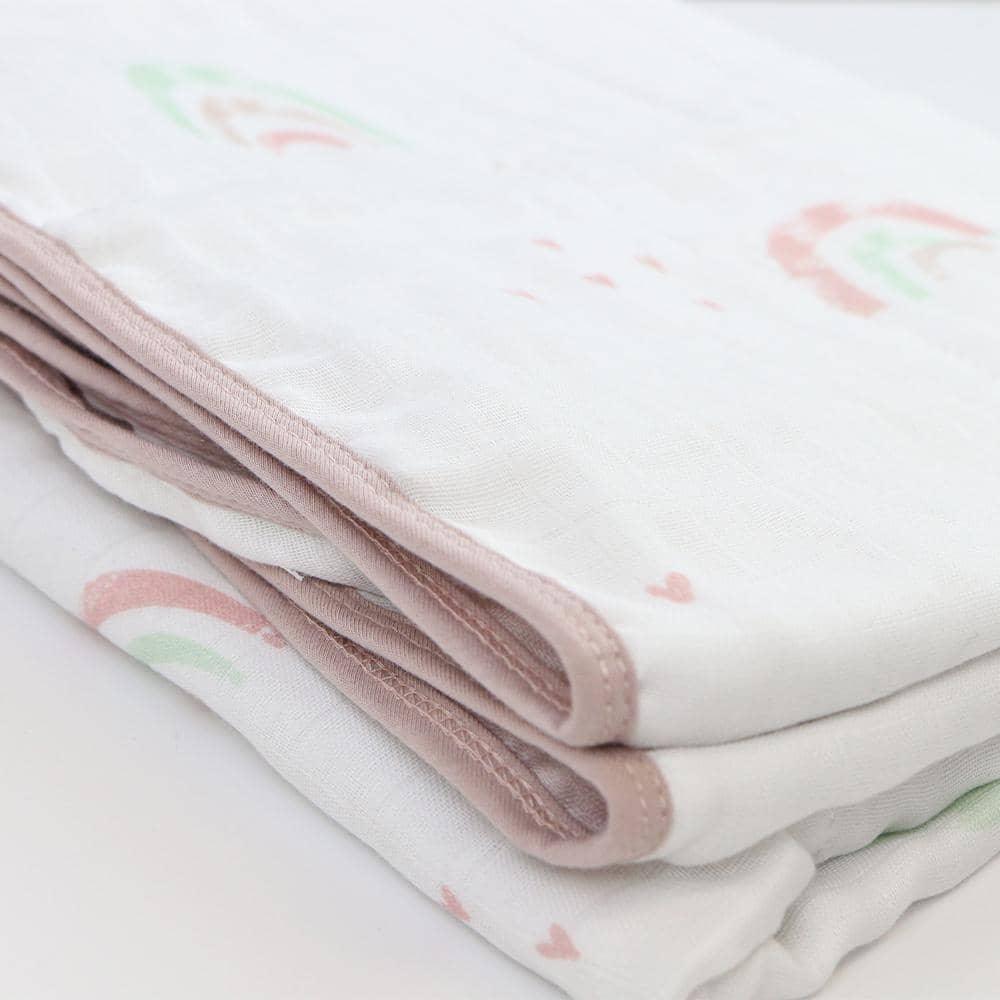 White bamboo muslin quilted blanket for newborns with pastel rainbow print and pink trim