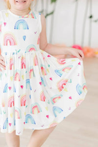 Little girl wearing rainbow tank twirl dress for girls holding the skirt and smiling