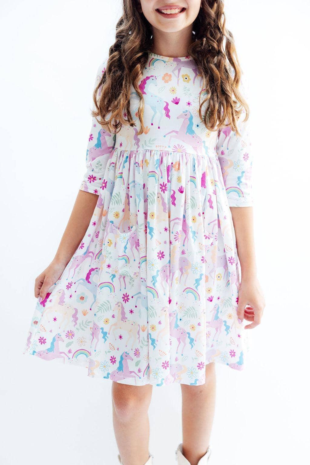 young girl wearing  rainbow twirl dress for girls with unicorn and rainbow print posing smiling