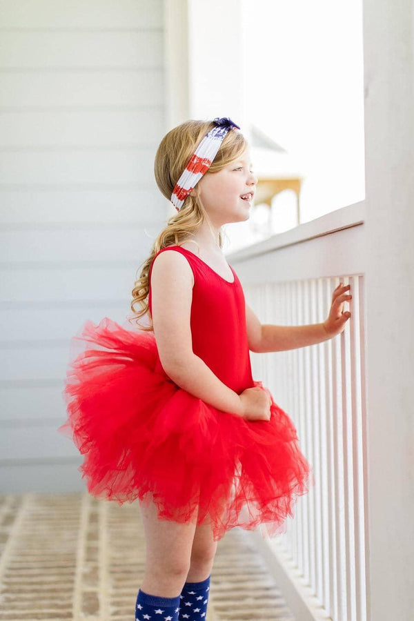 young girl wearing red tutu leotard standing and looking outside on porch railing