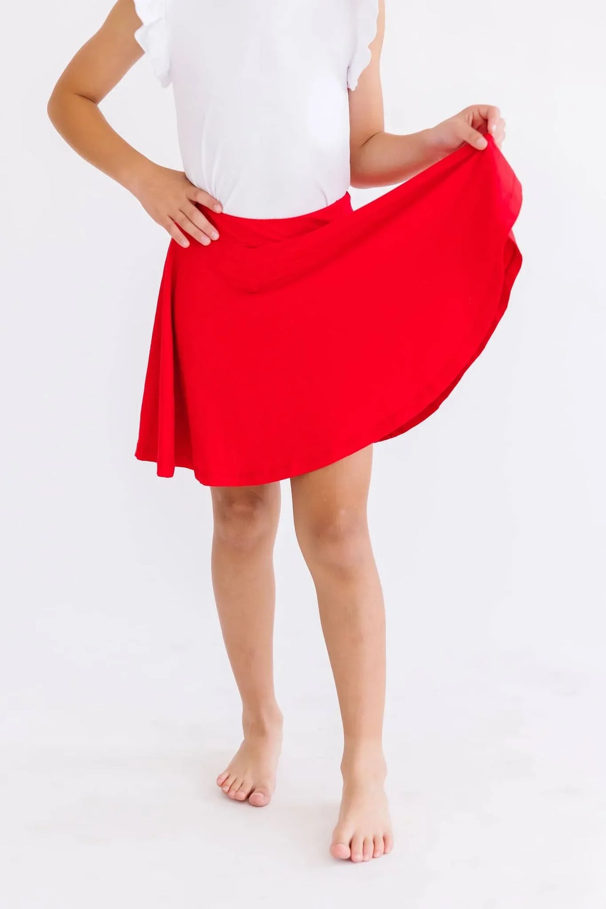 Girl wearing red twirl skort for girls holding out skirt in playful pose
