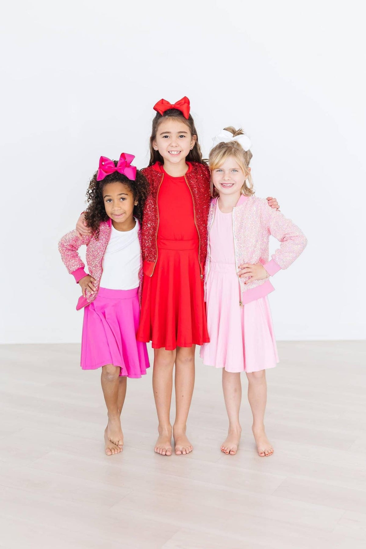Girl wearing red twirl skort for girls standing between two friends in pink outfits and bows
