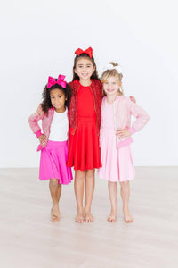 Girl wearing red twirl skort for girls standing between two friends in pink outfits and bows