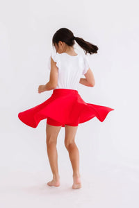 Young girl twirling in a red twirl skort for girls with a white flutter sleeve top