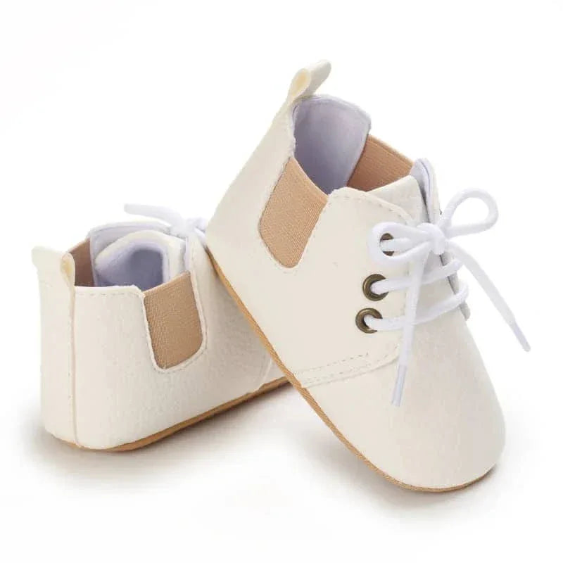 White retro baby lace-up shoes for infants with beige elastic side panels on a white background