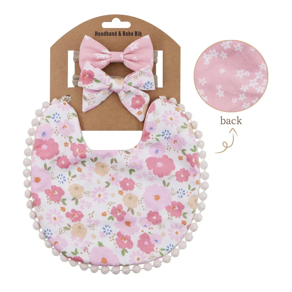 Pink and floral reversible baby bib and headband set for infants with pom pom trim and bow accessories