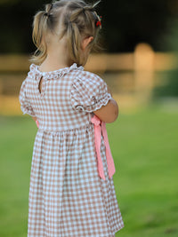 Back view of a vintage plaid dress with pink ribbons, ruffled sleeves, and a keyhole back on a toddler.