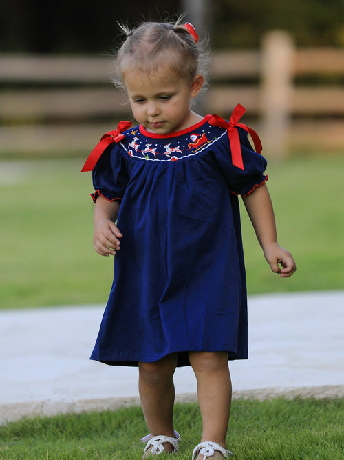 Navy Christmas dress with Santa sleigh embroidery and red shoulder bows for toddler holiday celebrations.