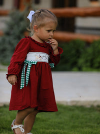 Red velvet Christmas smocking embroidered girls dress with festive dog motif and green plaid bow.