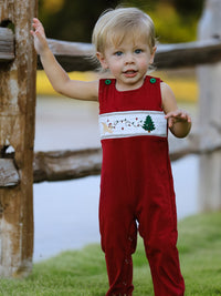 Toddler wearing red romper with festive Christmas tree and dog smocking embroidery, perfect for holiday photos.