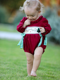 Baby girl in red Christmas romper with festive tree embroidery and green plaid side ties.