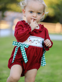 Red baby girls Christmas romper featuring festive reindeer embroidery and a green plaid bow sash.