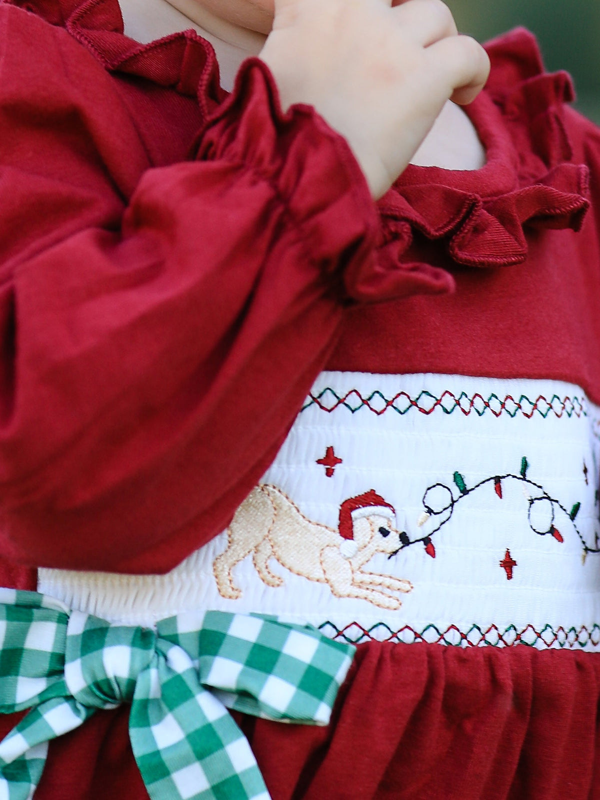 Red baby romper with festive dog embroidery wearing a Santa hat and green plaid bow.