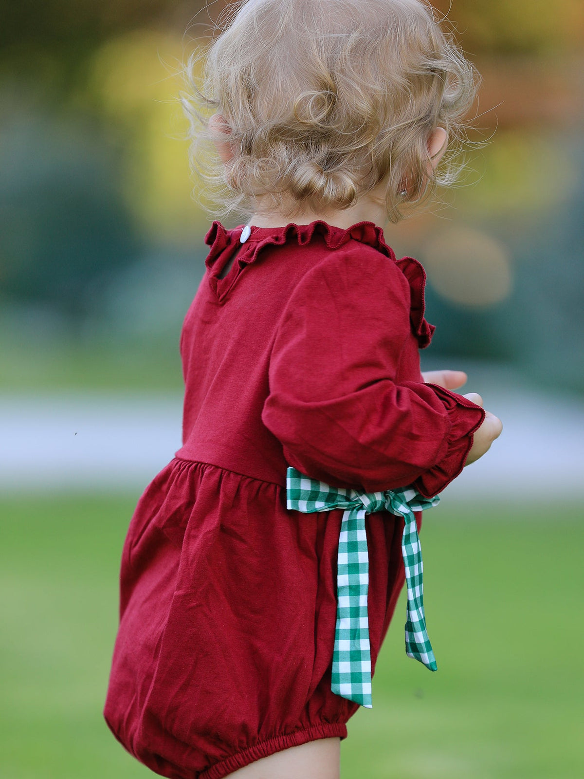 Red baby girls romper with ruffled sleeves and green plaid bow tie back for festive holiday wear.
