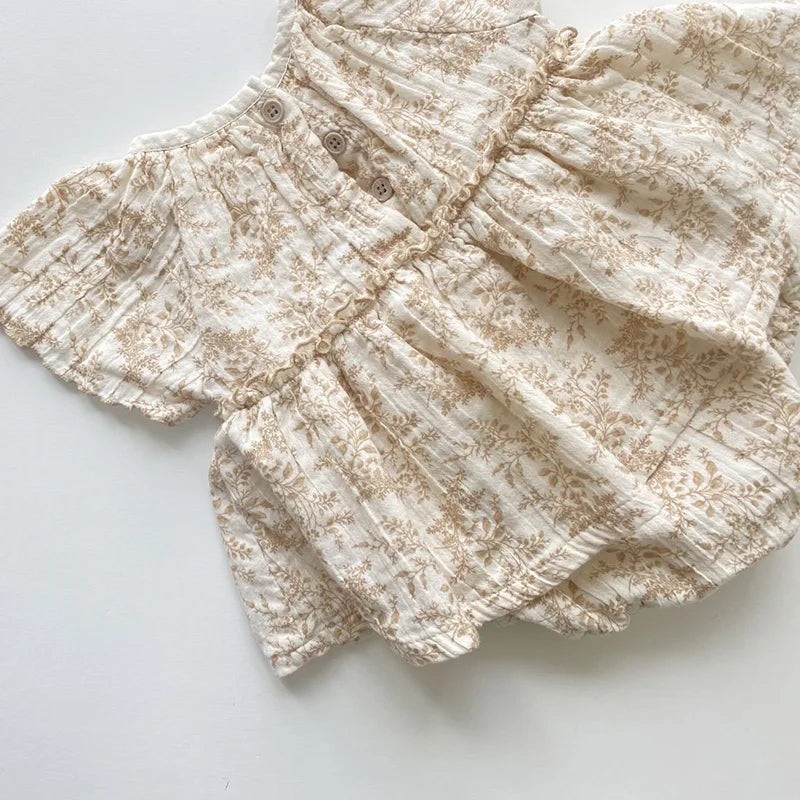 Cream-colored baby romper with beige floral print and button details for infants
