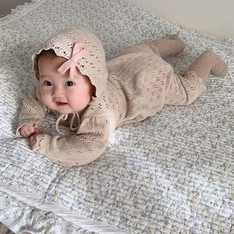 Beige knitted romper for babies with hood and pink bow detail, suitable for infants