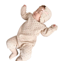 cream-colored knitted baby romper for newborns with matching bonnet and delicate pattern