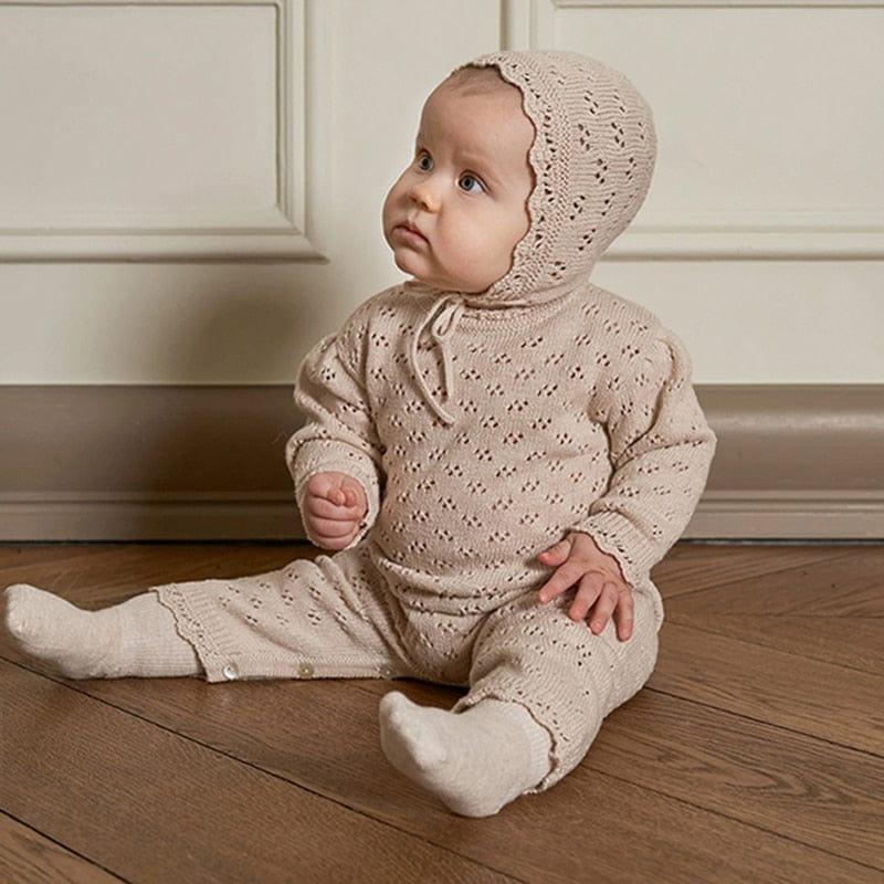 beige knitted romper with matching bonnet for babies featuring eyelet pattern and long sleeves