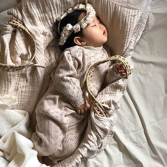 baby girl beige knit romper with long sleeves and eyelet pattern sleeping with matching headband