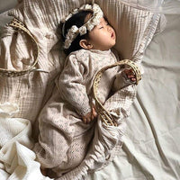 baby girl beige knit romper with long sleeves and eyelet pattern sleeping with matching headband