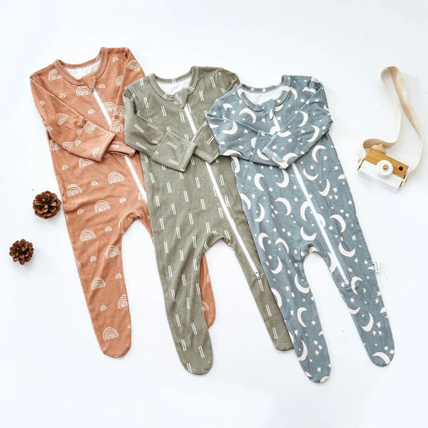 Set of three baby rompers in brown with rainbows, olive green with stripes, and blue with moons for newborns