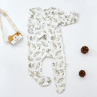 White baby romper with green leaf print, long sleeve, footed design for infants