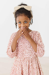 girl wearing rose gold velvet sequin dress for girls covering her mouth with hands