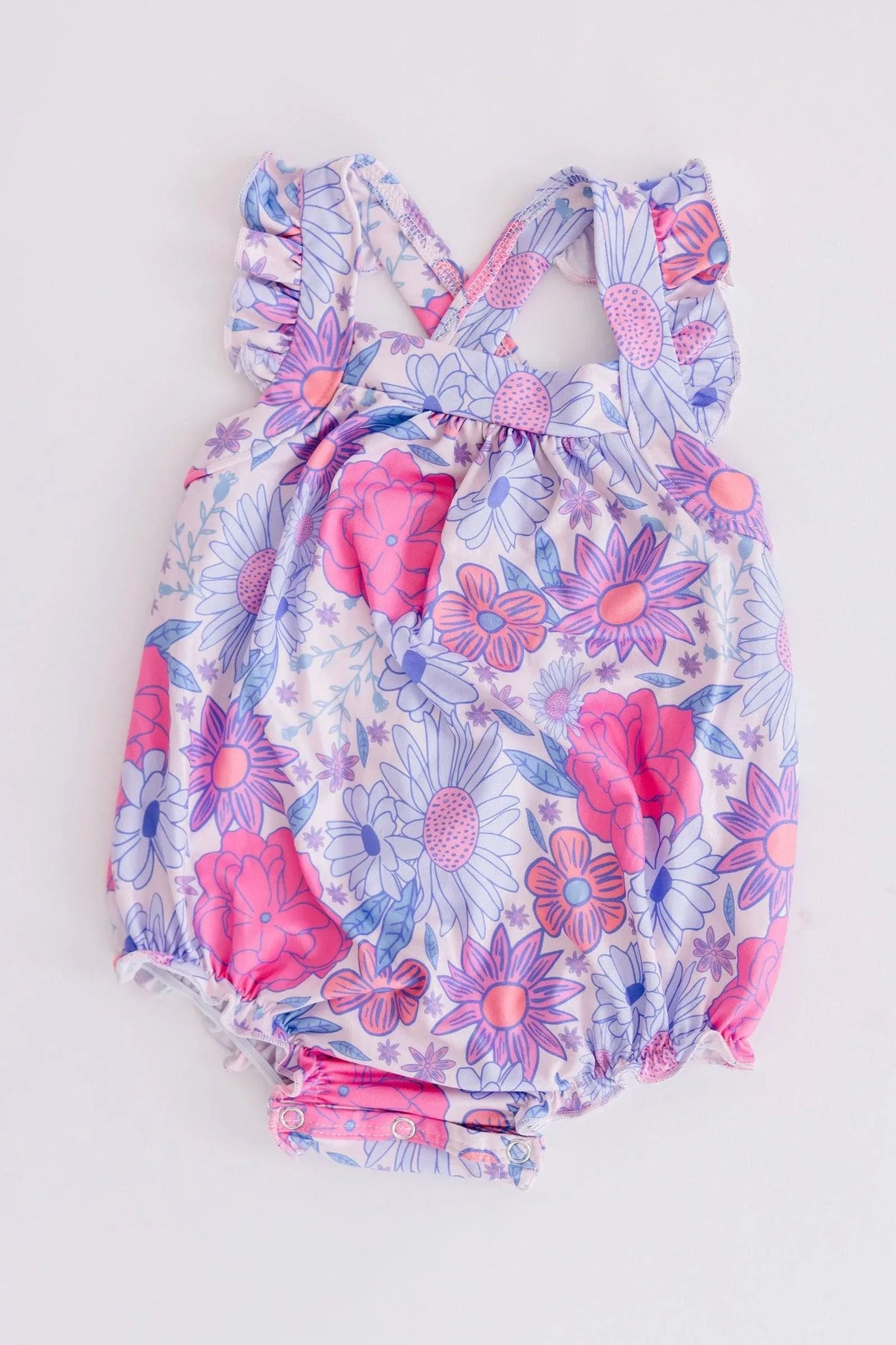 Baby girl sleeveless ruffle cross back romper with pink and purple floral print laid flat