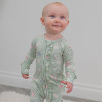Baby wearing Mint Butterfly Daisy Bamboo Ruffle Baby Footie with butterfly and daisy print.