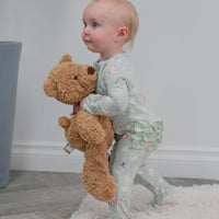 Baby wearing Mint Butterfly Daisy Bamboo Ruffle Footie, hugging a plush teddy bear