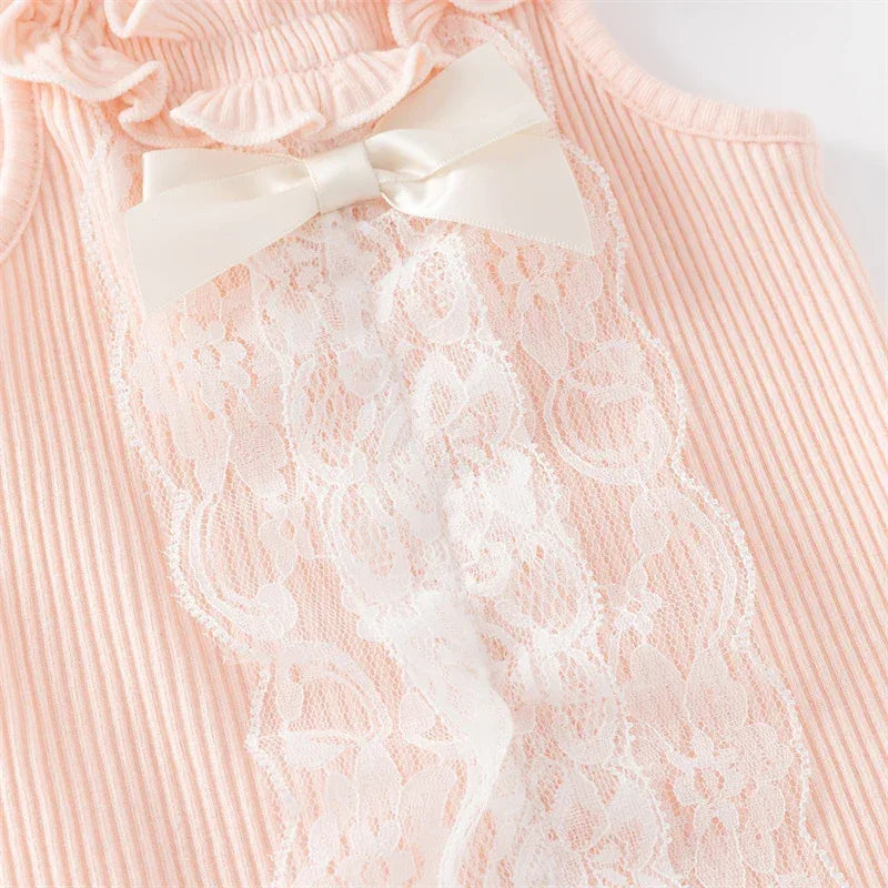 Close-up of pink ruffle knit baby romper with white lace and satin bow detail for infants